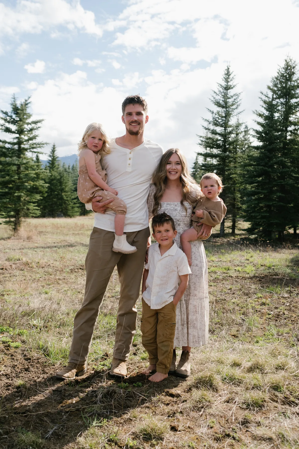 Judah and Belle Draxlir with their three young children, standing in a pine meadow